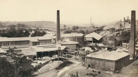Bill Fairclough Black and white photograph of the Farnworth Paper Mills in 1870. The image shows a Victorian industrial mill complex with chimneys. 