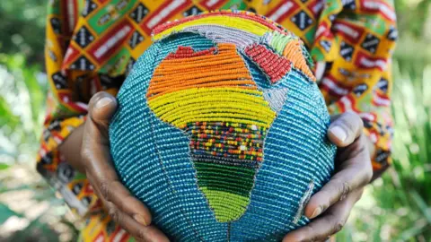 Woman holding a beaded globe of Africa