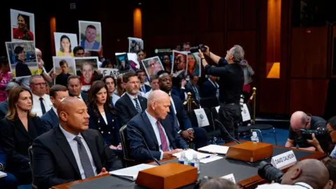 Getty Images Family members hold signs behind Mr Calhoun as he speaks