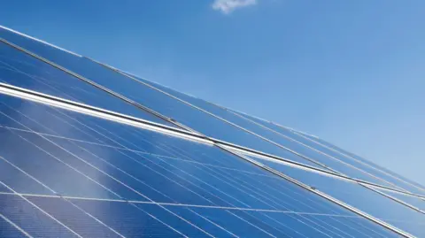 An aerial view of solar panels on the roof. The sky is blue and clear.