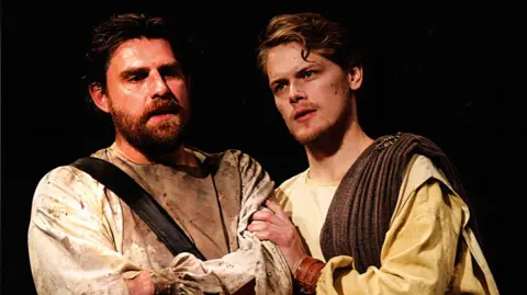 The Royal Lyceum Theatre Edinburgh Sam Heughan, right, wearing a robe, with a brown sash over his right shoulder.