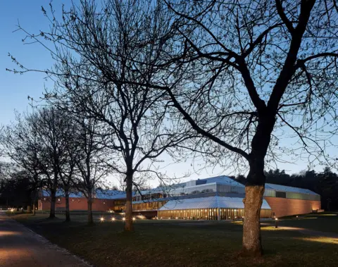 Hufton and Crow Outside view of the Burrell Collection at dusk, the building lit by warm lights