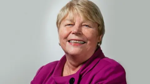 Baroness Jenny Randerson smiles at the camera. She is wearing a purple top.