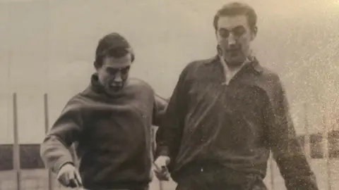 Ken Wagstaff A black and white image showing two male football players, both wearing training tops.