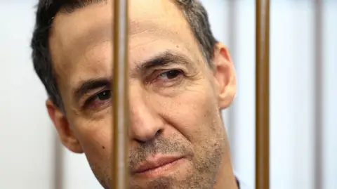 French researcher Laurent Vinatier watches on as he sits behind bars at a Moscow court