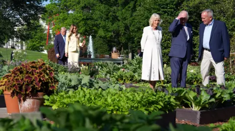 Reuters Britain’s King Charles III talks with Dale Haney, superintendent of the White House grounds, as they walk in the garden with U.S. President Donald Trump, first lady Melania Trump and Queen Camilla