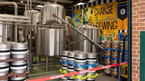 Tap Social The Tap Social Brewery with a colourful mural on the wall reading "Change is Brewing". There are No Entry signs in front.