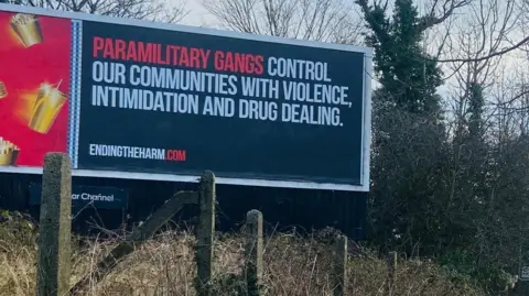 A sign saying: "Paramilitary gangs control our communities with violence, intimidation and drug dealing."