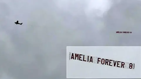 A light aircraft pulls a banner behind it reading: Amelia Forever 8
