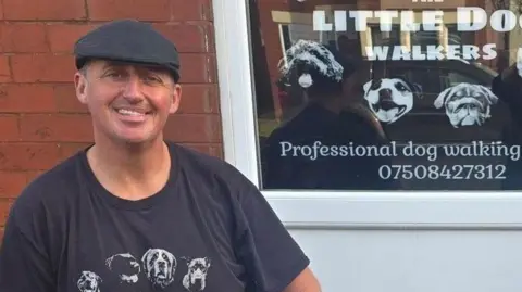 Darren Mason has a black cap and wears a black T-shirt with his business name on it
