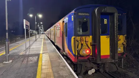 A red, yellow and blue South Western Railway Class 455 at Hampton Court station.