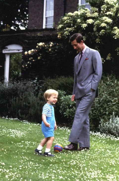 PA Media Young Prince William and young King Charles III kicking small football round in the garden