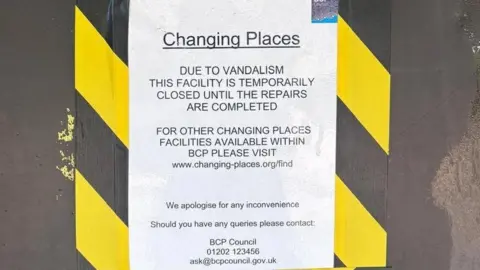 Patricia Risbridger A printed paper sign is stuck to a door with black and yellow tape. It reads: "Due to vandalism this facility is temporarily closed until the repairs are completed. For other changing places facilities available within BCP please visit www.changing-places.org/find. We apologise for any inconvenience."