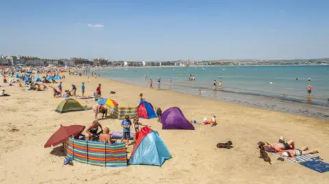 Weymouth Beach with crowds of people sunbathing.