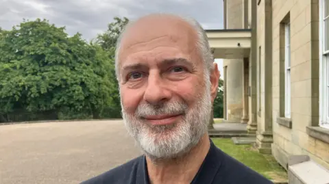 Fabian Hamilton, who has short grey hair and a grey beard. He has brown eyes and is smiling in the headshot.