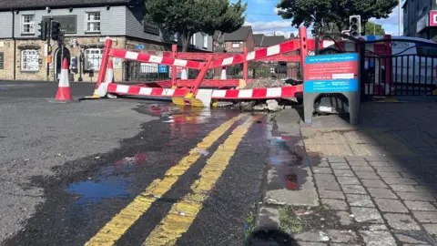 Water leaking from a hole which has been cordoned off on a main road
