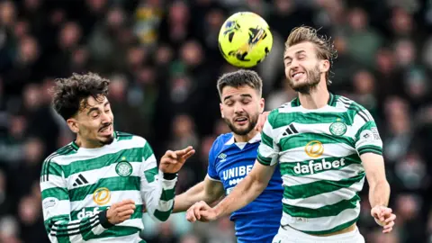 Celtic and Rangers players challenge for the ball