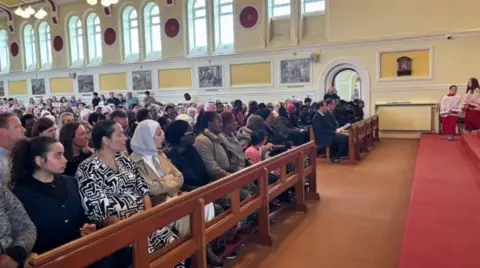 A large crowd sitting in seats inside a church.