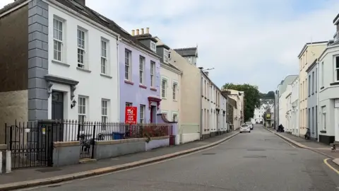 BBC St Helier residential streets - rows of houses on either side of a main road