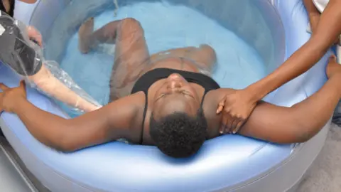 Getty Images A pregnant woman sits in a blue, inflatable birthing pool to give birth