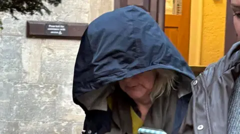 PA Media Jane Barnard looks to the ground as she leaves Gloucester Crown Court, her face is obscured by the navy blue hood of a rain jacket