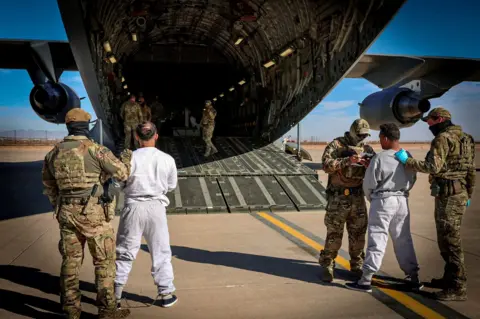 Detained US migrants arrive to a detention facility at Guantanamo Bay 