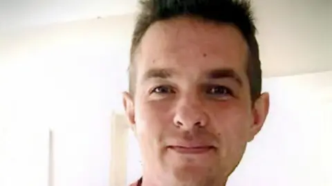 Northamptonshire Police Nicholas Billingham is looking at the camera. He has short brown hair and brown eyes