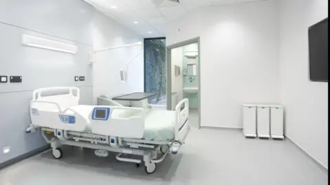 Airedale NHS Foundation Trust The image is a graphic representation of a patient room. It has a hospital bed in the middle of the room and an ensuite bathroom visible in the background.