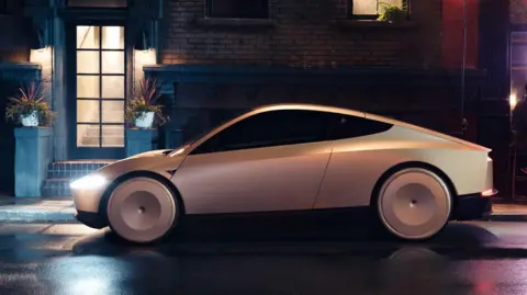 A Tesla Cybercab is parked on a dark, dimly lit street at the Warner Bros. studio in California