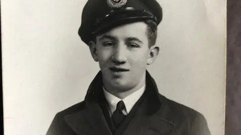 Family handout A teenager is wearing a merchant navy uniform, including a coat, tie, shirt and a hat.