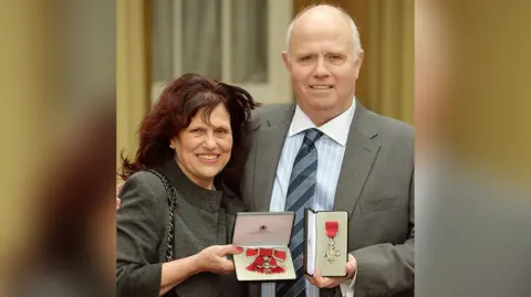 Getty Images Mr and Mrs Mizen holding their MBEs