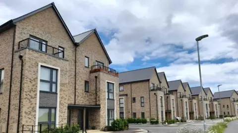 A row of new build semi-detached yellow brick three-storey houses at Alconbury Weald, Huntingdon