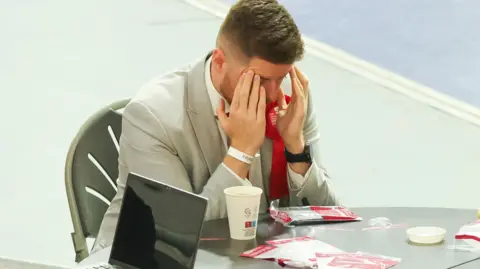 Jon Rowley/Getty Images Labour candidate Chris Cater with heads to his forehead, looking down at a table.