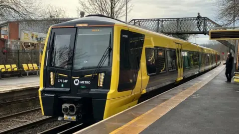 A new looking yellow and black train stopped at a train station