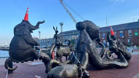 Statues of different animals in Boston with orange traffic cones on their heads.