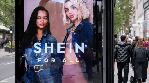 Getty Images A bus stop advertising screen displays an add for Shein featuring two women, one wearing a denim jumpsuit and the other wearing pink activewear and a denim jacket.