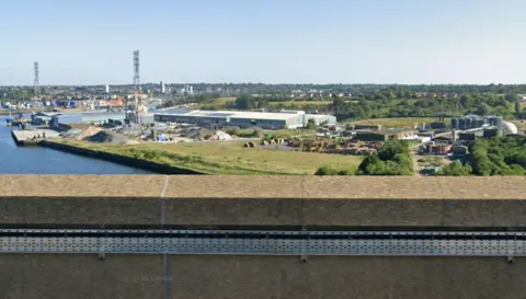 Googlemaps View of Cliff Quay taken from a bridge. Shows a small patch of green land where the wind turnbine would site. Buildings and pylons sit behind