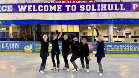 Girls on Tour The ladies are wearing their black uniform and posing on the ice in front of a Welcome to Solihull banner.