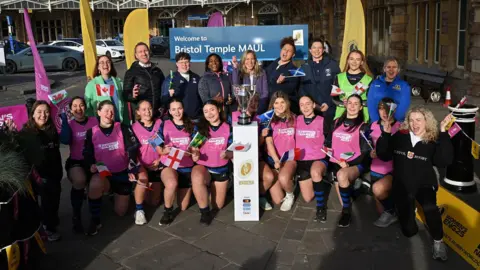 Getty Images A large group of people stand outside Bristol Temple Meads station to launch ticket sales for the Women's Rugby World Cup 2025. Behind them is a large sign showing the name "Bristol Temple Maul" It is a sunny day and the group, mostly women, is smiling at the camera