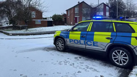 A police car parked in a street in the snow.