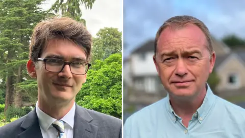  Markus Campbell-Savours (left) and Tim Farron (right). Campbell-Savours has brown hair and is wearing a grey suit. Farron has short brown hair and is wearing a blue shirt