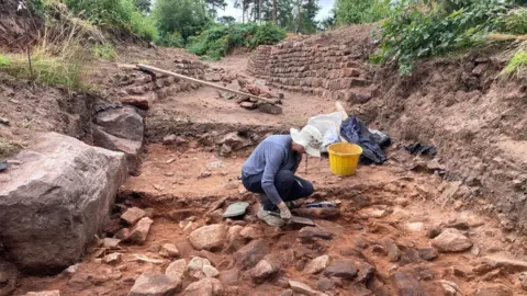 Archaeologists searching through rocks at a hillfort