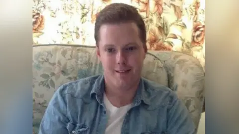 A picture of Jack Stephens from Burgess Hill who died after wood plank fell from the Travis Perkins lorry and went through his windscreen in May 2020. Jack, who was 28 when he died, has short brown hair and is wearing a blue denim shirt and white t-shirt. 