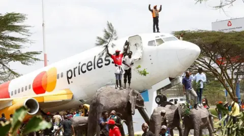 Reuters Mourners stand on a grounded aeroplane and elephant sculptures