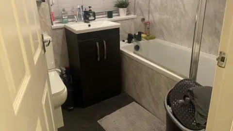 Simon Thake A small neat bathroom with beige bath and basin.