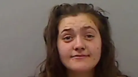 Cleveland Police Mugshot of Waite. She has messy thick long brown hair and marks all over her face.