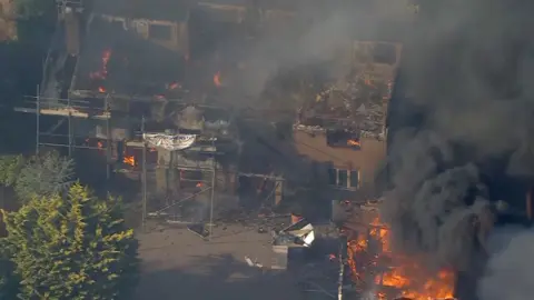 Aerial footage showing plume of black smoke and flames engulfing destroyed houses house 