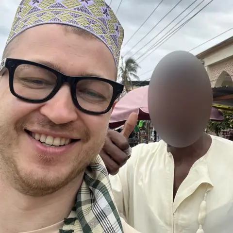 Photo via Fotostrana.ru Man wearing dark-framed Ray Ban branded clear glasses with a little camera visible above the wearer's left hand lens. He's wearing a traditional hat with a yellow and purple diamond pattern.