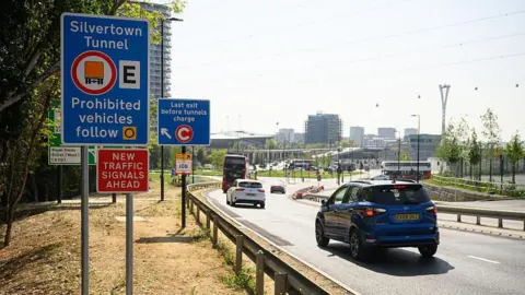 Getty Images Road leading to the Silvertown Tunnel with traffic and roadside signs warning restricted vehicles and indicating the last exit before the tunnel charge.