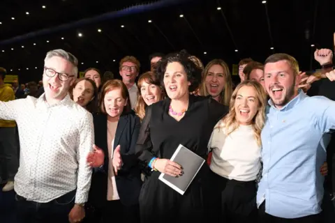 Getty Images Claire hanna in black with supporters at election count centre Titanic